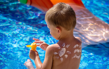 Mother puts cream on her son's back. Caring for baby skin. Sunscreens in the travel. selective focus