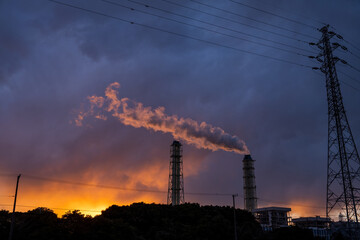 黄昏時の光の中を流れる煙突の煙