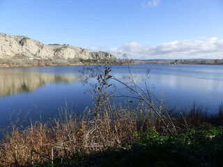 Lagoon with fishermen on a sunny day surrounded by reeds and mountains