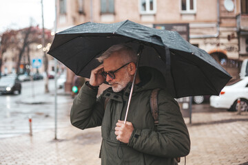 Migraine and headache when the weather changes. Unpleasant symptoms in a mature man in the rain.