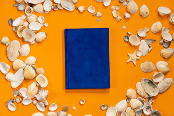 Notepad, shell and seashells on orange background for mockup. Relax beach summer sea concept. Plans for summer to do list