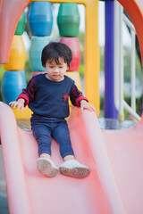 Fototapeta na wymiar Littleboy playing on slide at park playground.