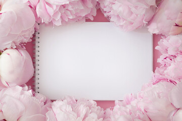 Romantic spring layout, top view image of pink fresh peonies, open blank notepad. Place for messages, ads, text