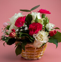 Basket of flowers on a pink background. Beautiful bouquet of flowers.