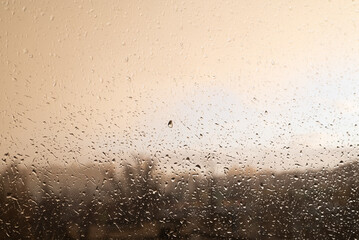 Raindrops on the glass during cloudy weather and a blurry image of the city.