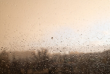 Obraz premium Raindrops on the glass during cloudy weather and a blurry image of the city.