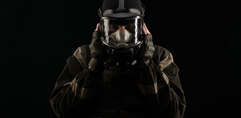 a man in a military uniform and a gas mask holds with an angry expression of emotions on a black...