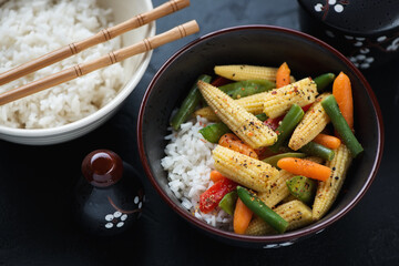 Middle close-up of two bowls with vegetable stir-fry and white rice, selective focus, horizontal shot