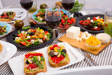 Top view of many plates with tasty vegetarian food and wine in glass