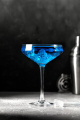 Blue cocktail in high glass with ice on grey background. Blue lagoon. Barmen equipment