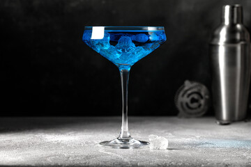 Blue cocktail drink with ice in glass. Alcohol drink on gray background