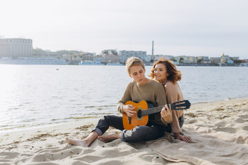 Fototapeta na wymiar Happy couple in love. Stunning sensual portrait of a young couple. Young man playing guitar for his beloved girl.
