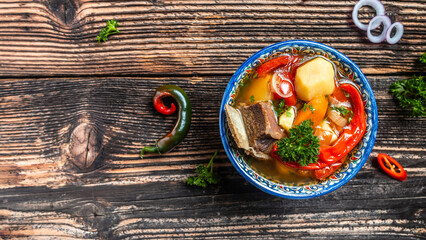 Shurpa soup in plate with oriental ornament, wooden background. Top view. traditional Asian, Uzbek,...