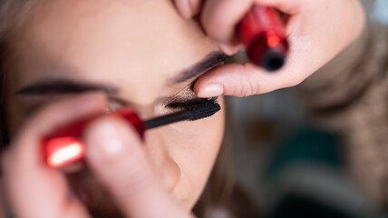 Make-up artist applies mascara to the girl's eyelashes, close-up