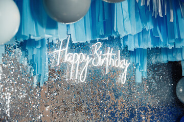 luxurious glowing neon inscription happy birthday on the wall decorated with silver candies and...