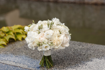 large beautiful wedding bouquet of white roses on a stone slab