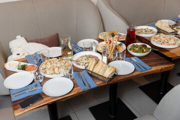 dining wooden table for a family with different salads, cheese, prosciutto and fresh herbs