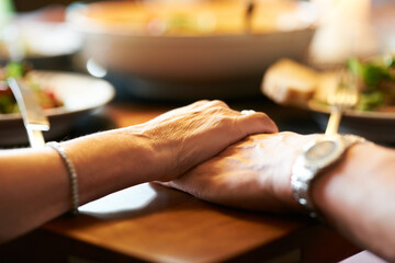 We have each other. Cropped shot of a couple holding hands in prayer at the table before eating.