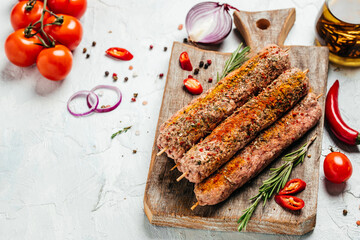raw Lula kebab on skewers with spices on a cutting board light background. Lula kebab, traditional Caucasian dish. Long banner format. top view