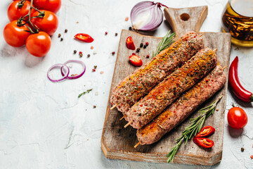 raw Lula kebab on skewers with spices on a cutting board light background. Lula kebab, traditional...