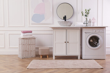 Laundry room interior with modern washing machine and stylish vessel sink on countertop