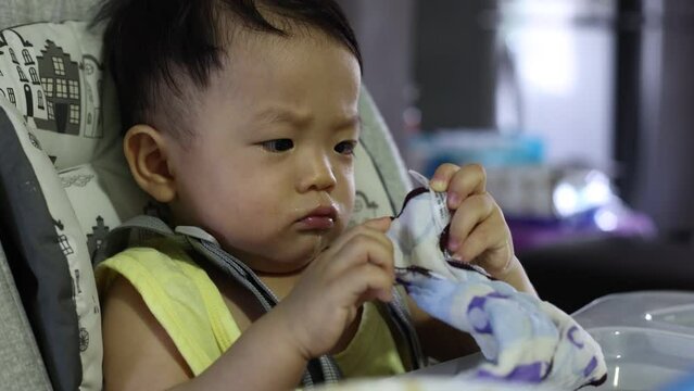 Potrait footage of adorble and cute happy Asian Chinese baby boy sit on baby chair with face expression