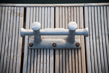 Double cross bollard or bitteng with a tied rope on the dock. towing mooring gear