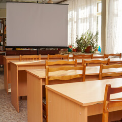 An empty school classroom with a white screen