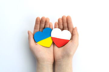Children's hands hold two hearts with flags of ukraine and poland on white background. Unity solidarity help concept - obrazy, fototapety, plakaty