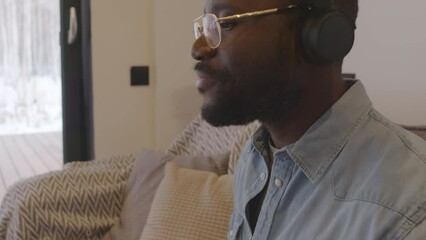 Man sitting on couch drumming with pencils on his knees