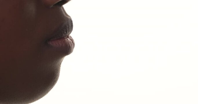 Close Up Side View Of An Black Woman's Mouth While Eating A Pink Macaron. Isolated On A White Background.