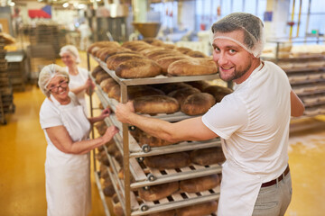 Bäcker Team schiebt einen Regalwagen mit frischen Broten