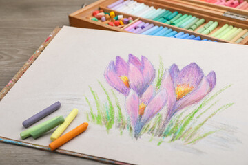 Beautiful drawing of crocus flowers and pastels on wooden table