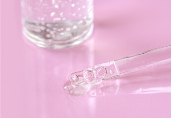 Pipette with fluid hyaluronic acid on pink background. Cosmetics and healthcare concept closeup. Dose of serum, retinol with air bubbles. Flat lay. Luxury beauty product presentation, macro