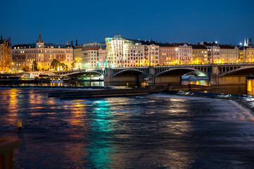 perspective to a dancing house of the night prague at dusk from the side of the Vltava River