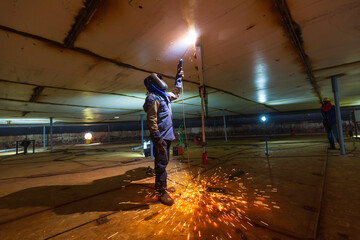 Welding male worker metal is part of machinery plate roof tank beam construction flash spark