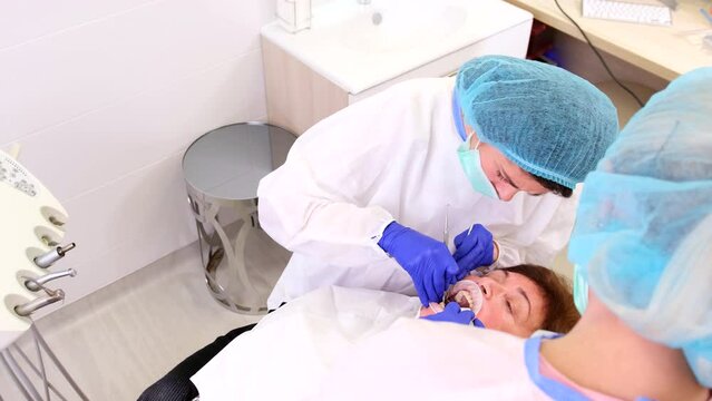 Top video of a doctor dentist with an assistant working in stomatological clinic treating woman patient teeth.