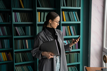 A female secretary works in a coworking space, uses a laptop and makes a report on the project.