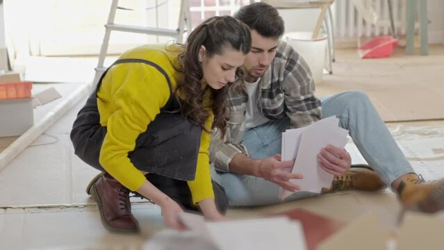 Couple sorting papers sitting on floor of new home