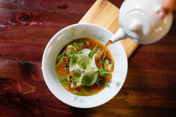 The process of pouring soup into a bowl top view. Original serving of soup.