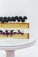 Sponge cake decorated with blueberries. Cake on a white background. Culinary skill. Confectionery on a white base.