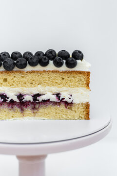 Sponge cake decorated with blueberries. Cake on a white background. Culinary skill. Confectionery on a white base.
