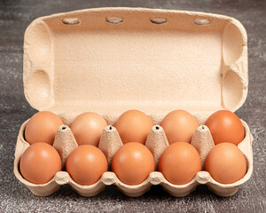 Fresh organic chicken eggs in open carton pack or egg container on brown background, set 11 of 12, stock photo