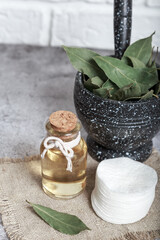 Laurel natural oil in a glass bottle. Cosmetic homemade tonic. Bay leaf in mortar with pestle
