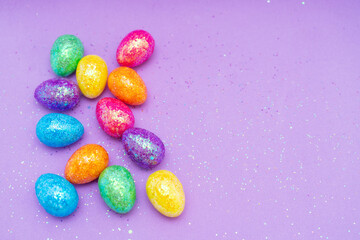 Fototapeta na wymiar Multi-colored Easter eggs on a purple background. Holiday concept with copy space.