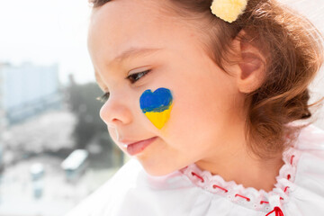 Little Ukrainian girl in an embroidered shirt on a white background. A little girl in national Ukrainian clothes - vyshyvanka. Little Ukrainian girl with a patriotic flag.