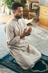 Prayer is devotion. Shot of a young muslim man praying in the lounge at home.
