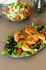 Finished tapaca chicken with a crispy crust lies in a plate on a bed of fresh vegetables. A homely atmosphere and a feast. Recipe for cooking chicken. Georgian national dish.