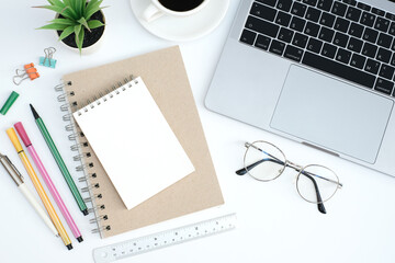 Work form home or online learning concept on white table desk with blank notepad and laptop computer with stationery, social distance during quarantine, self-isolation, online education concept