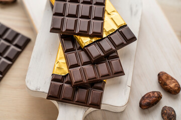 Chocolate bars with open gold cover. Stack of chocolate bars with cacao beans. Flat lay composition with delicious chocolate isolated on white background. Space for text